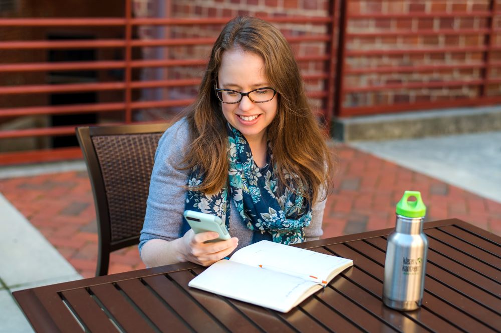 Data Soapbox owner sitting at a table, looking at her phone and planner